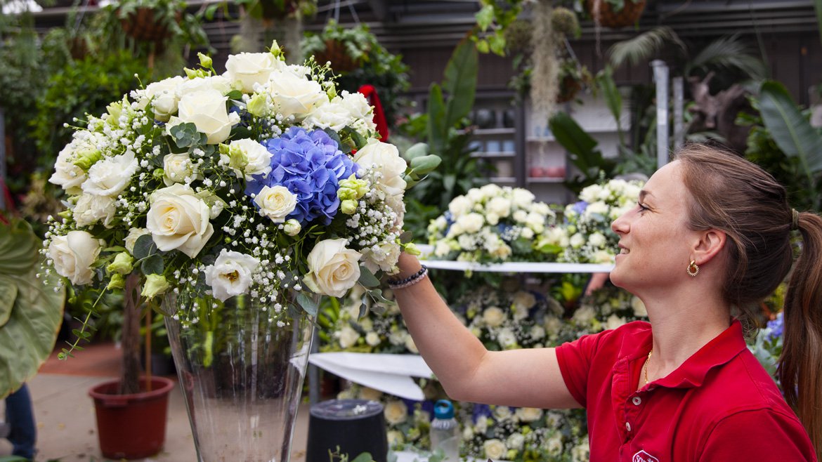 Décoration florale pour un mariage composé de rose blanche et hortensias bleu-violet, posé dans un grand vase pour centre de table - Schilliger Fleurs