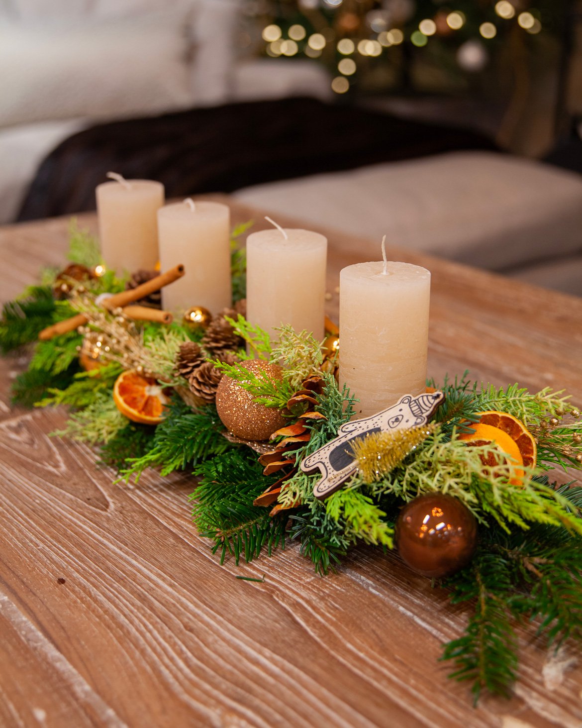 Centre de table créé par nos fleuristes avec quatre bougie, du sapin et des décorations de Noël - Schilliger Fleurs à Gland